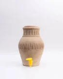 Eco-friendly Clay Cooler 5L with yellow tap and lid beside a white flower vase on table.